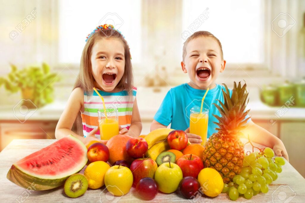 66088295 happy children with fruits and fresh juice in kitchen kids healthy eating concept