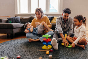 mom and dad playing with their kids in the living room at home two young parents having fun with their son and daughter during playtime family of four spending some quality time together JLPSF11335