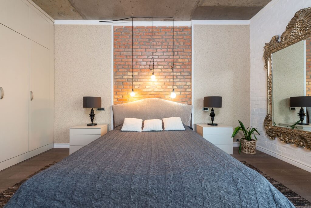 Bedroom with brick accent wall, pendant lights, and symmetrical nightstands