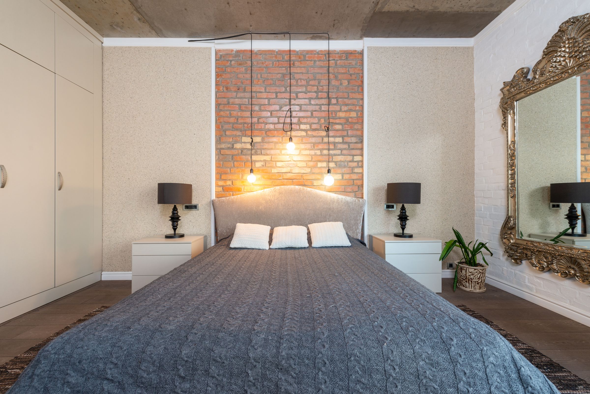 Bedroom with brick accent wall, pendant lights, and symmetrical nightstands