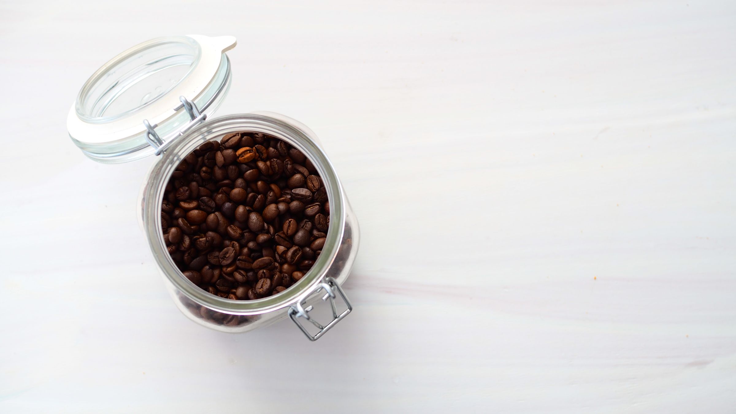 Home Coffee Bar Ideas That Feel Like a Real Café Corner 3 Matching glass canisters with wood lids filled with coffee beans