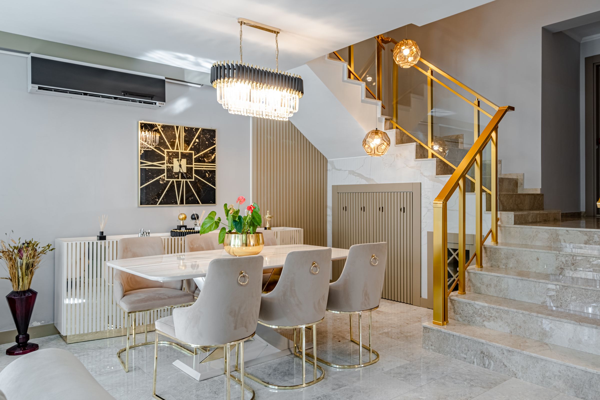 Elegant dining room with gold-accented table, velvet chairs, and chandelier