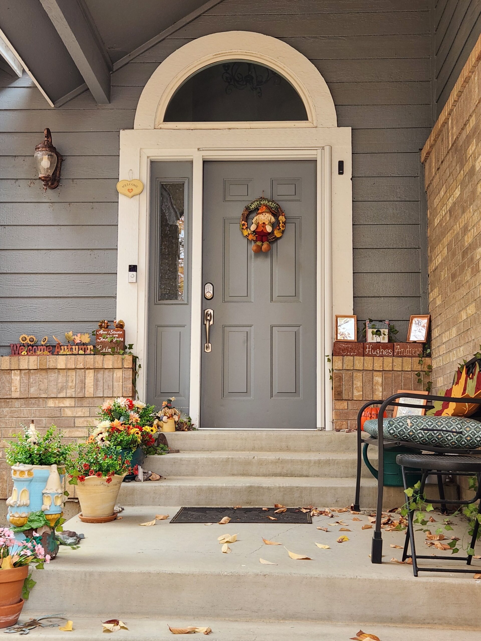 Full front porch with doormat, welcome sign, and seasonal flowers, photo by Anne Hughes via Pexels