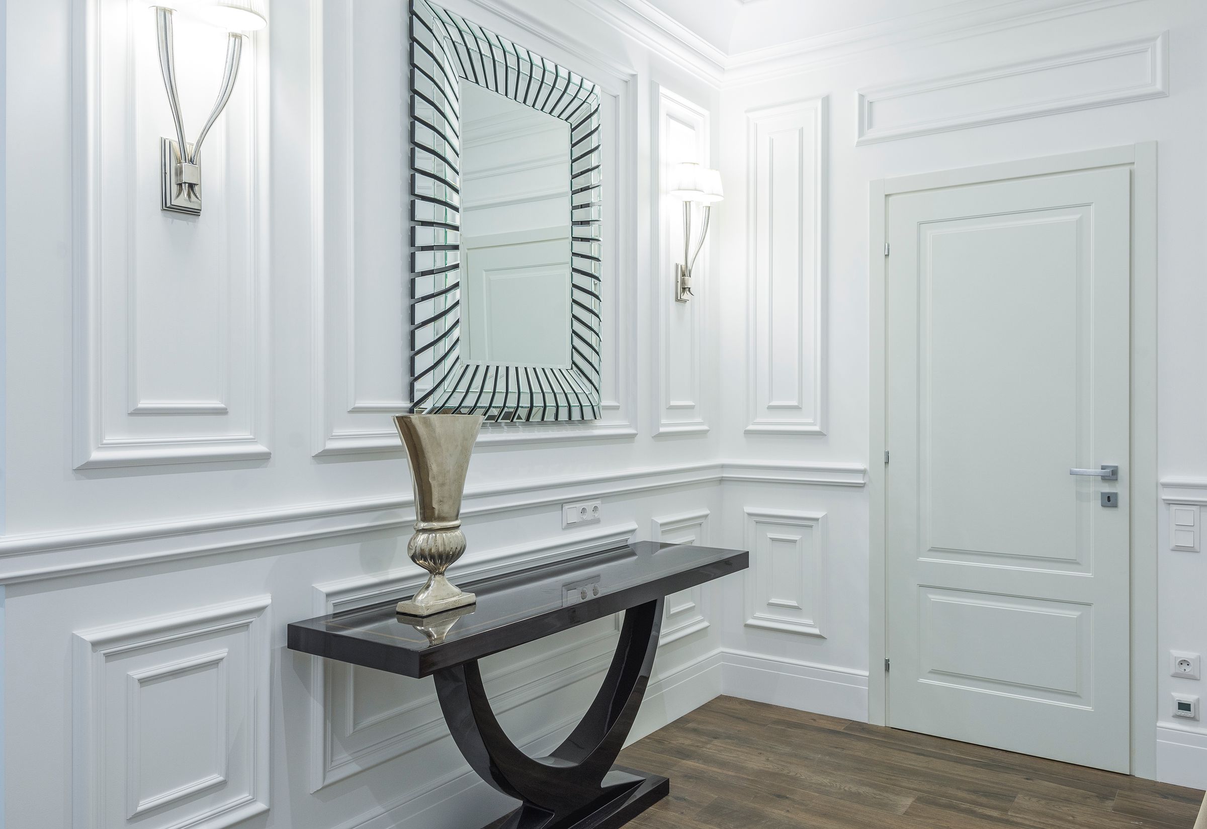 Elegant entryway with black console table, starburst mirror, and wall sconces