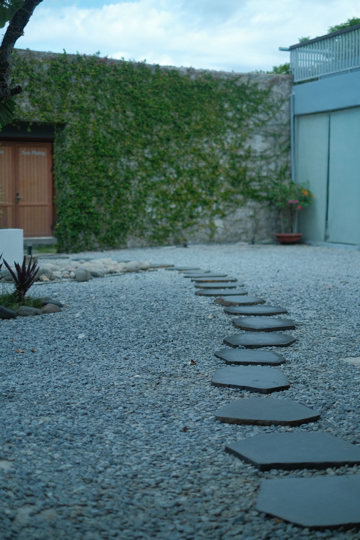 Outdoor path with stepping stones on gravel surrounded by greenery
