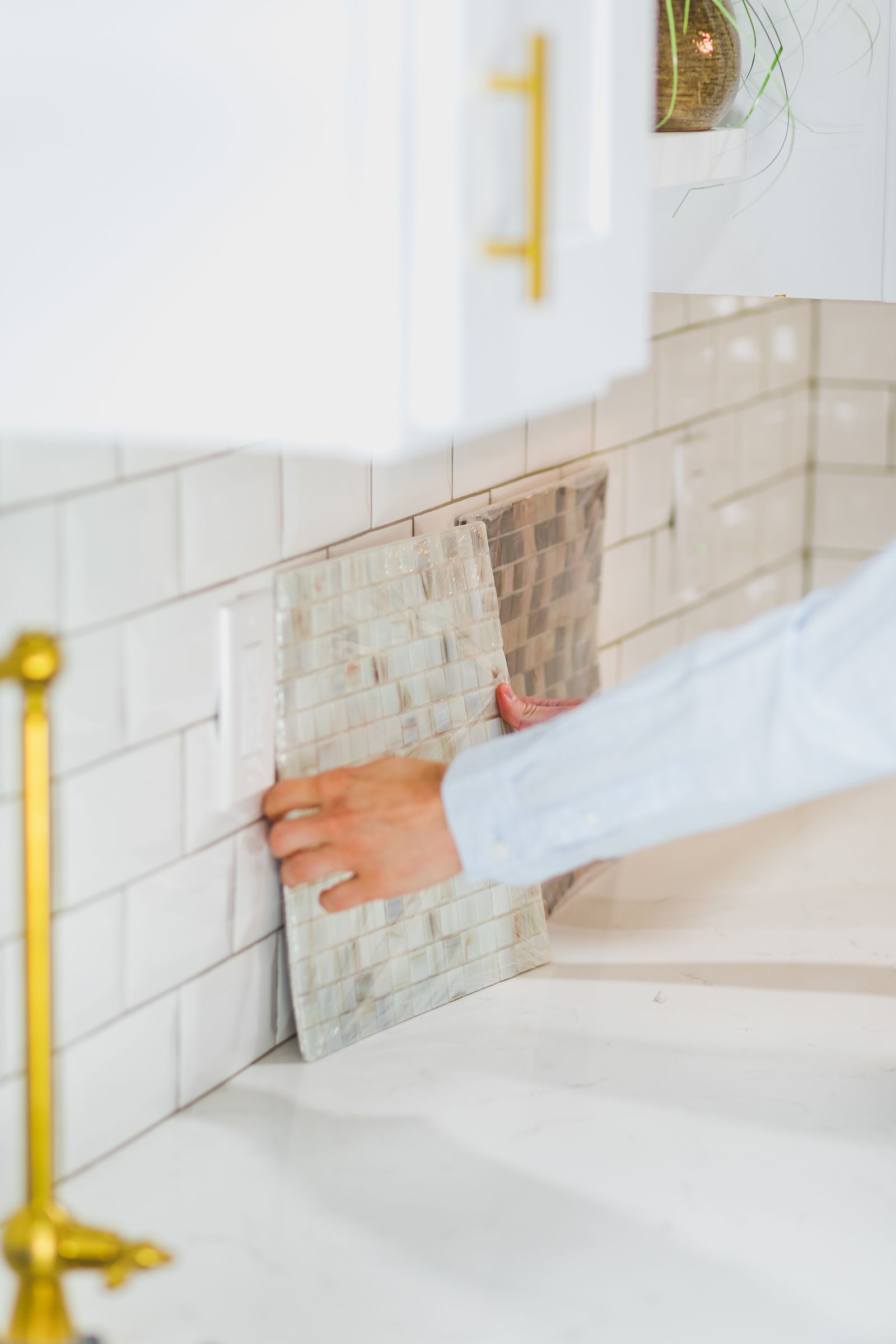 Person installing peel and stick tile backsplash in kitchen
