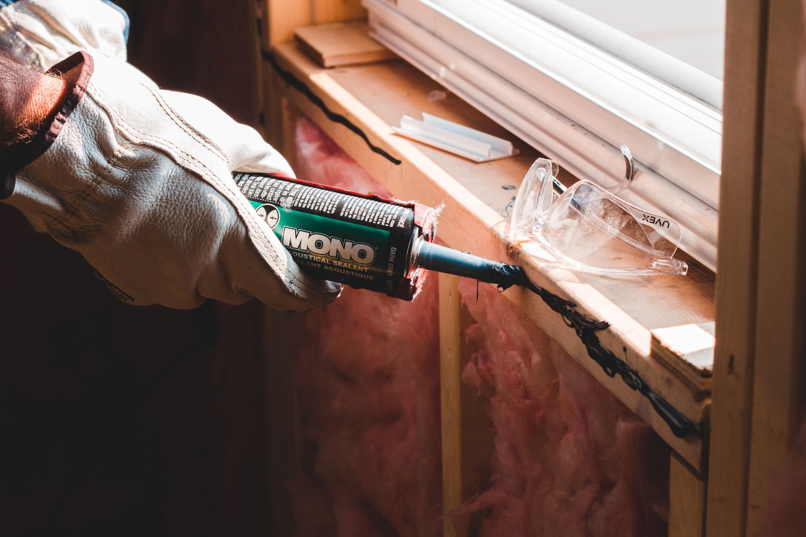 Hand applying fresh caulk sealant along a window frame