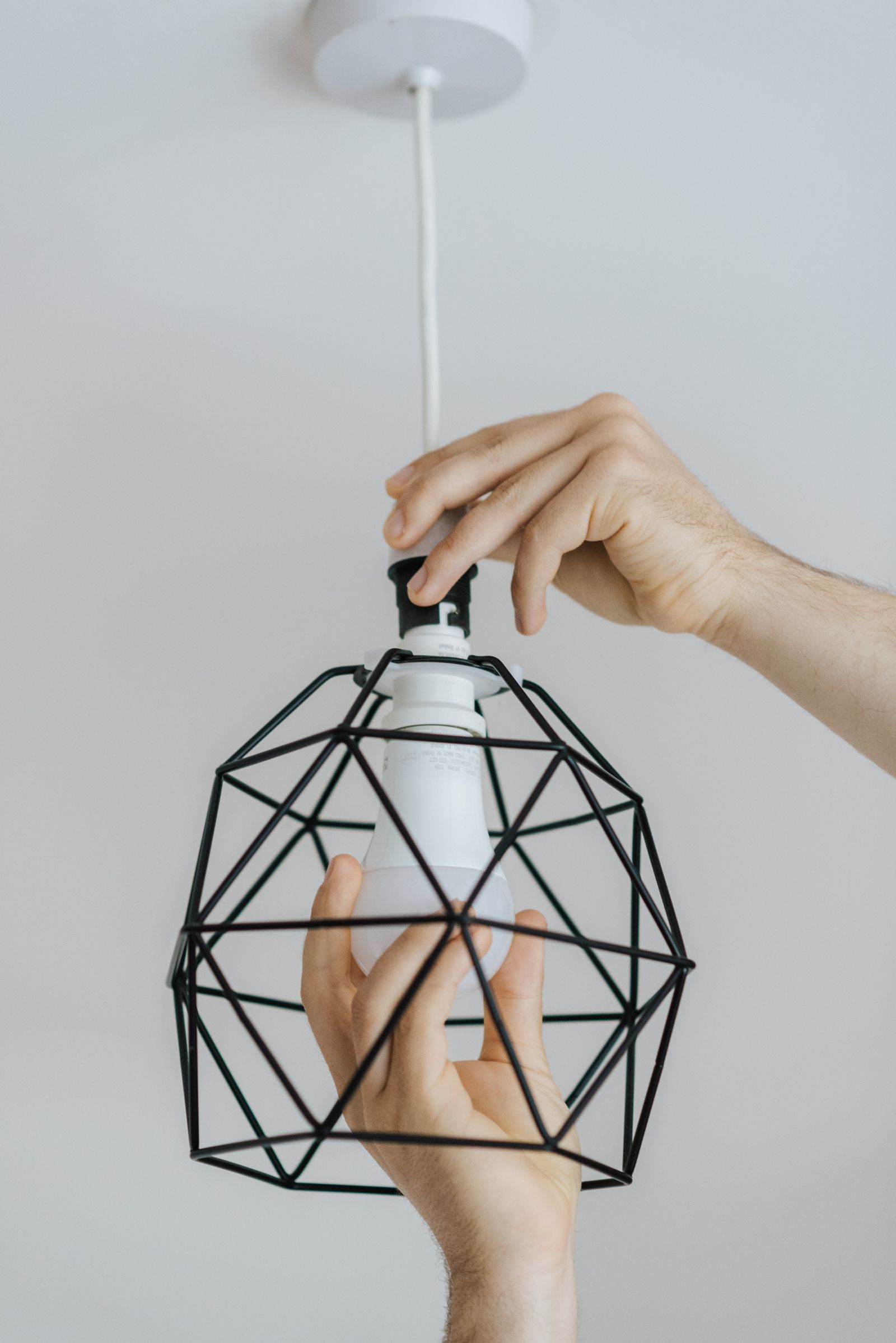 Hands installing a pendant light fixture bulb