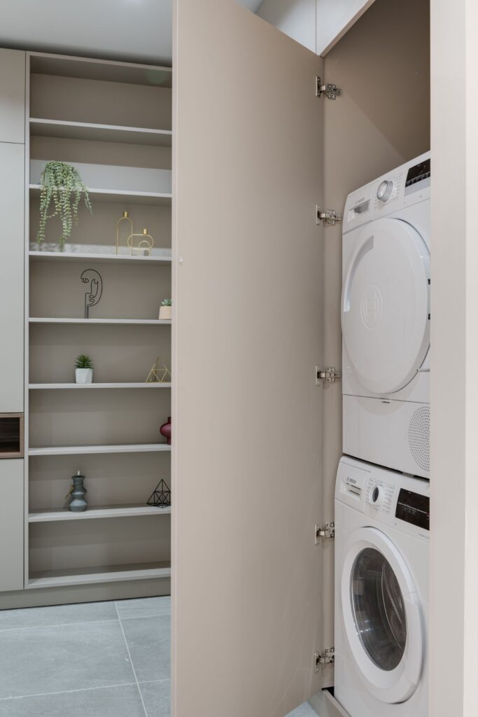 Built-in laundry closet with open shelving and stacked washer dryer