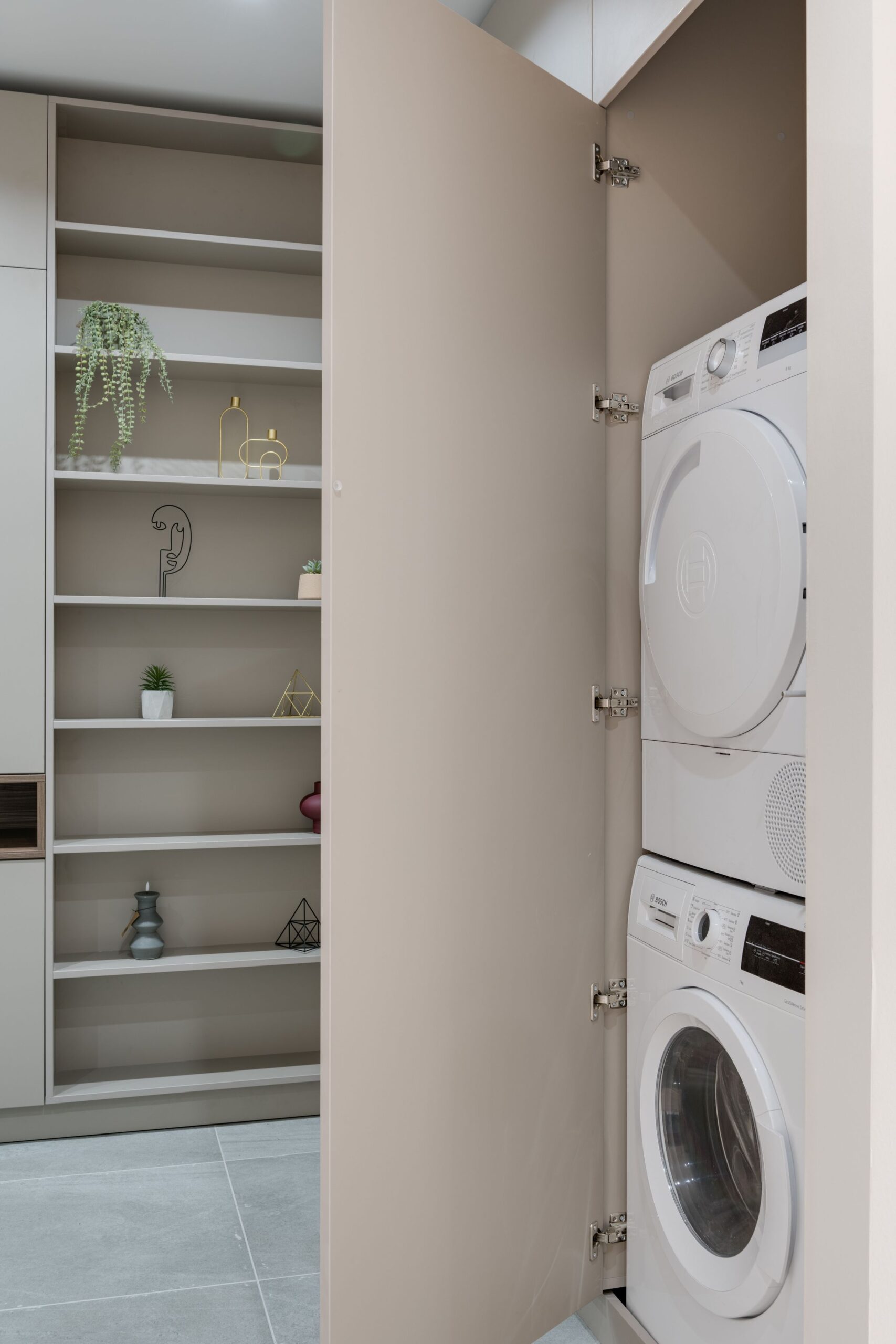 Built-in laundry closet with open shelving and stacked washer dryer