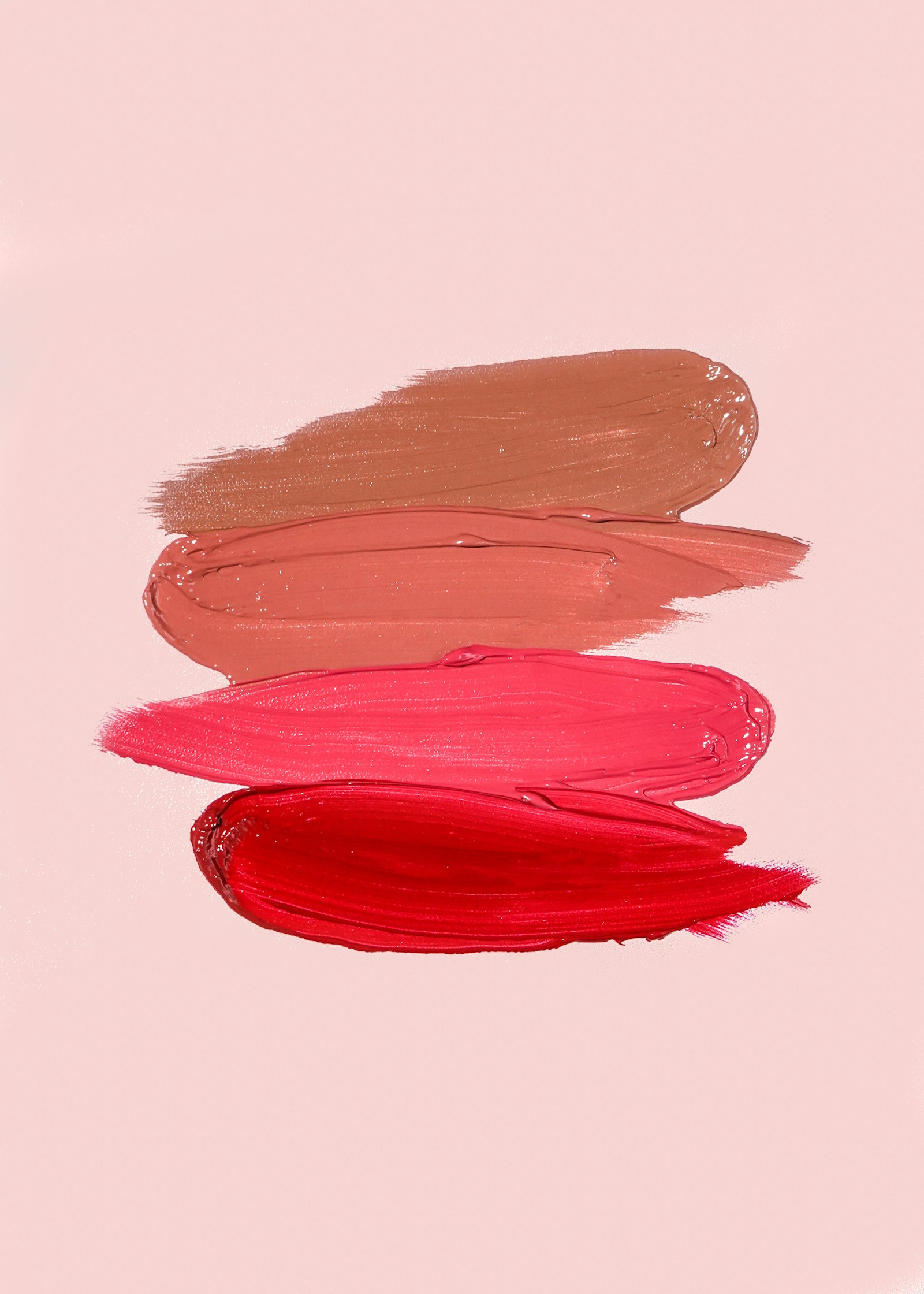 Four horizontal lipstick swatches in shades of brown, peach, pink, and red