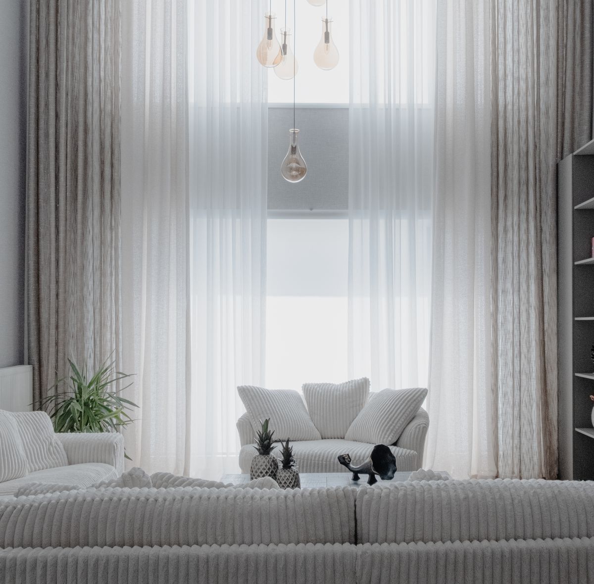 Minimalist living room with soft white sofas and large curtains