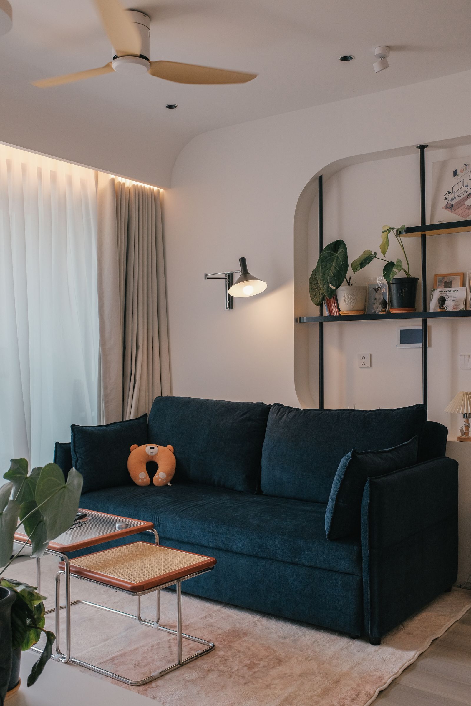Modern living room with a navy sofa, layered lighting, and plants