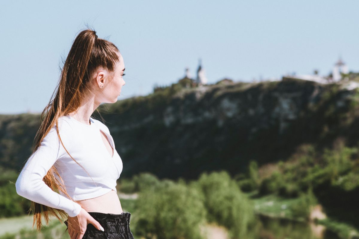 Woman with long layered hair gazing at a scenic landscape