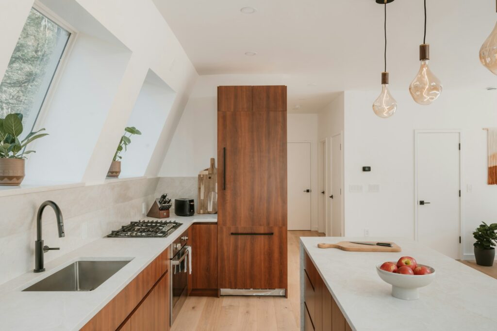 Modern kitchen with wooden cabinets, white countertops, and pendant lighting over the island