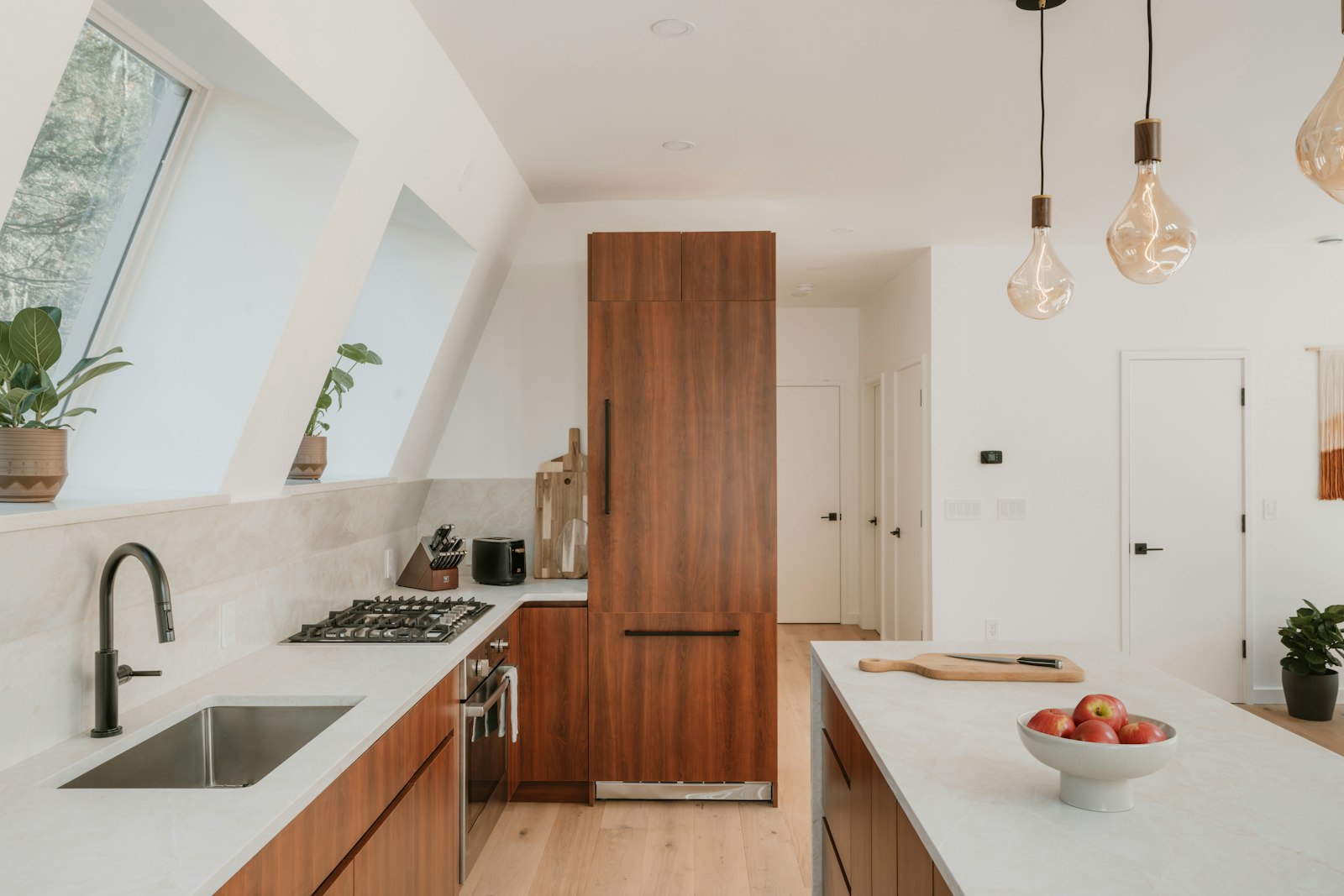 Modern kitchen with wooden cabinets, white countertops, and pendant lighting over the island