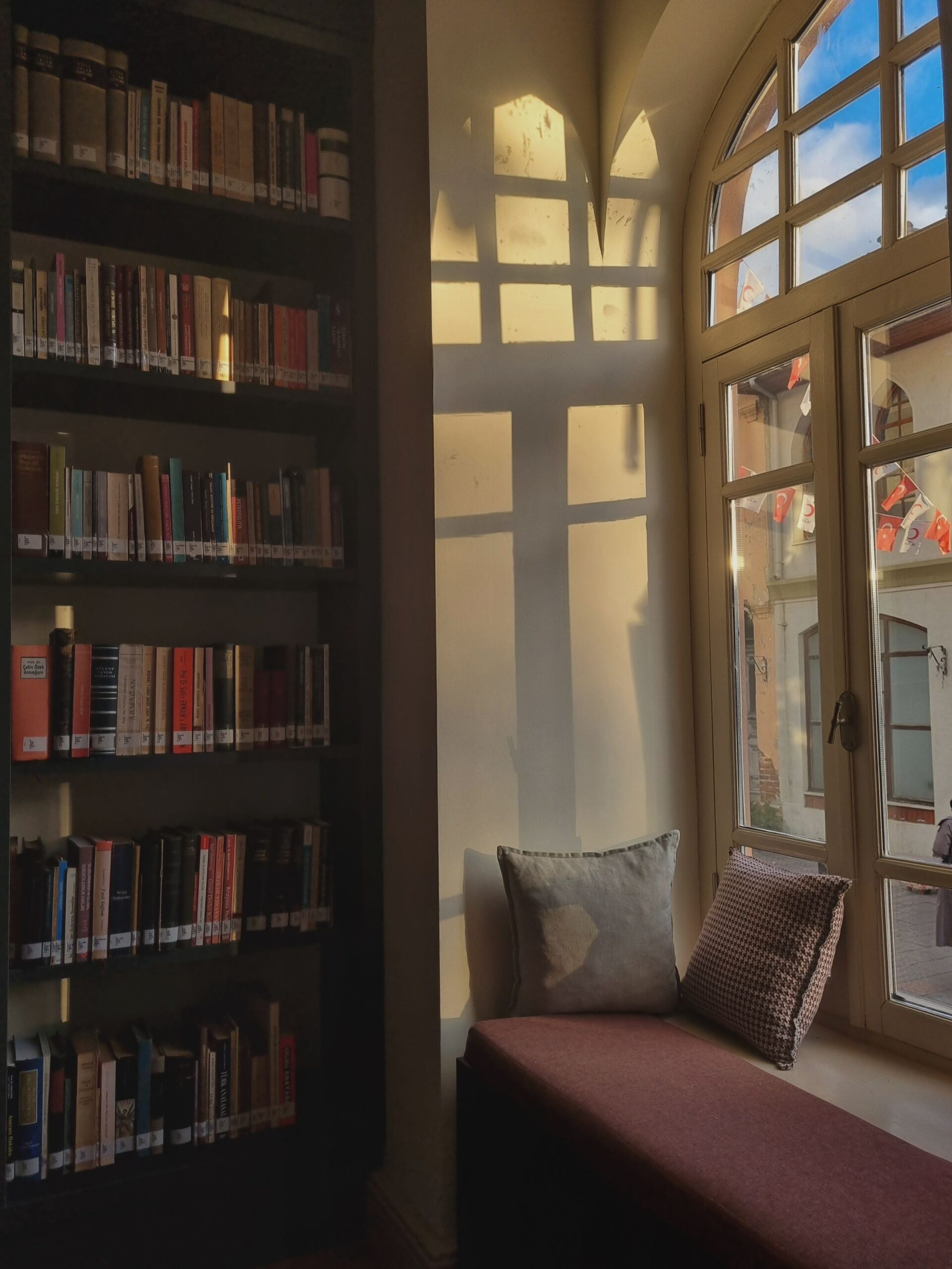 7 Cozy Reading Nook Ideas That Make You Want to Sit Down and Stay 3 Tall bookcase standing near a window framing a reading corner