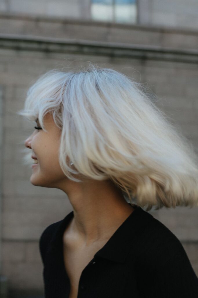 Woman with platinum blonde hair smiling outdoors