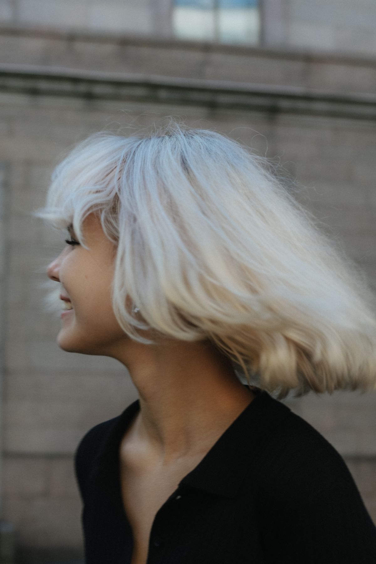 Woman with platinum blonde hair smiling outdoors