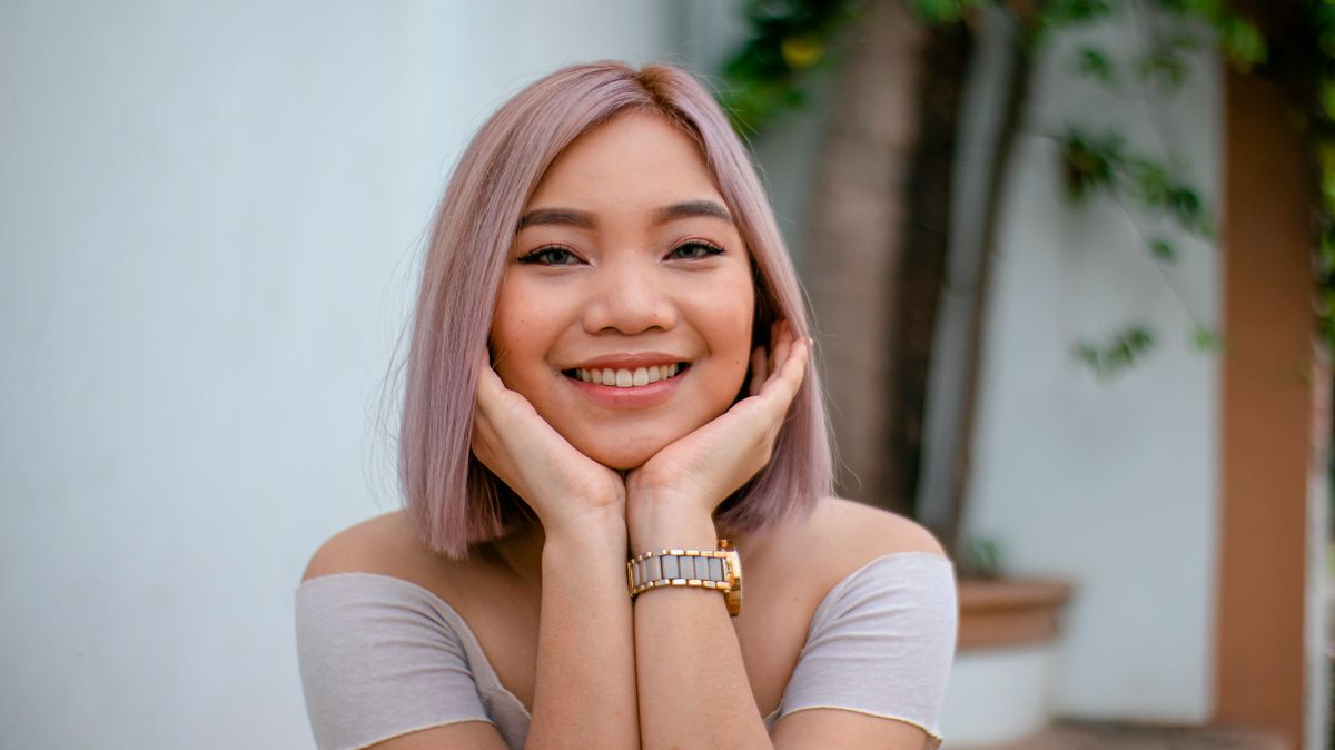 Smiling woman with rose gold hair outdoors