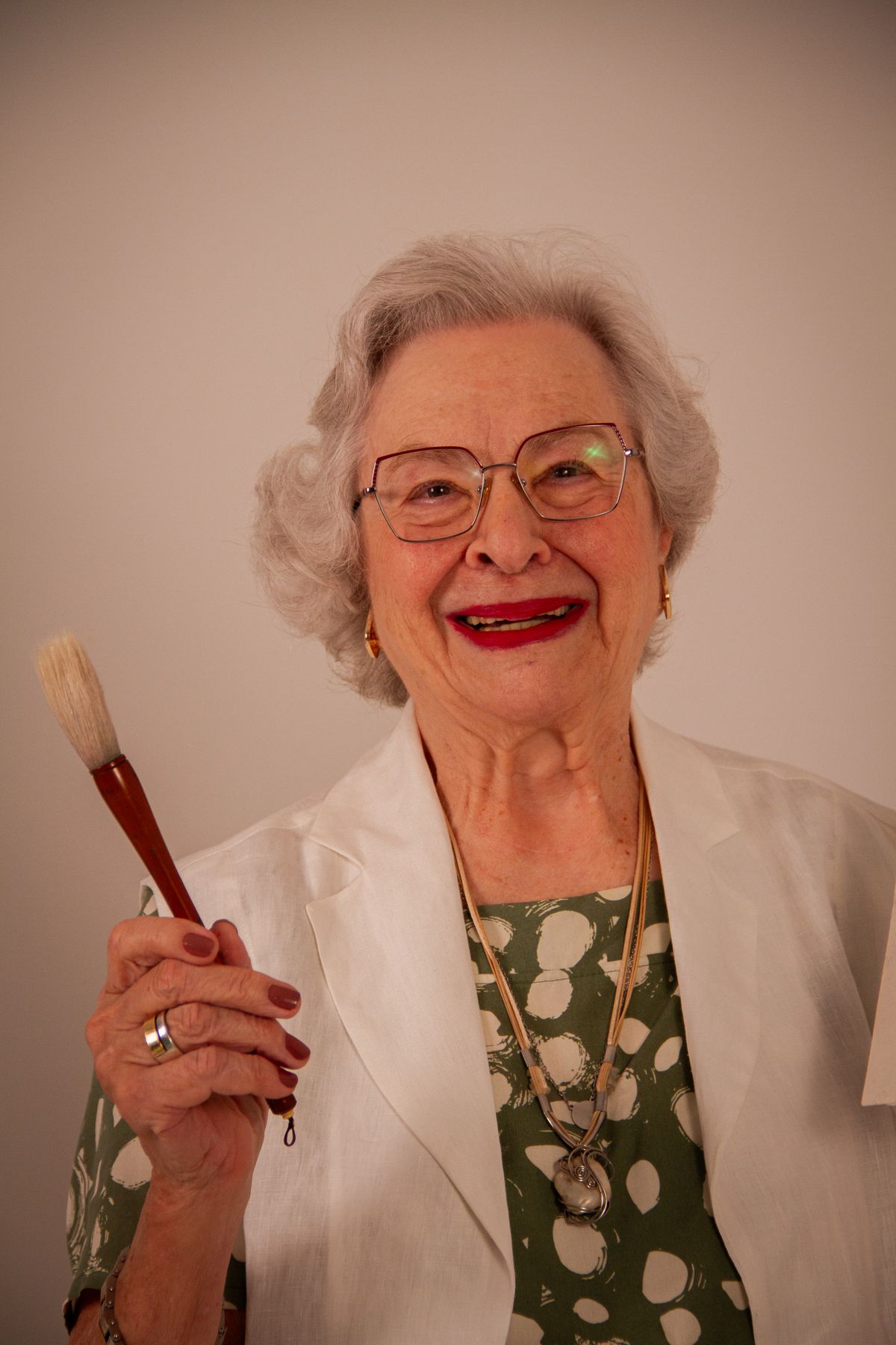 The Beauty, Strength, and Wisdom of Older Women: Embracing Life with Confidence 4 Elderly woman smiling with a paintbrush, showing artistic enthusiasm