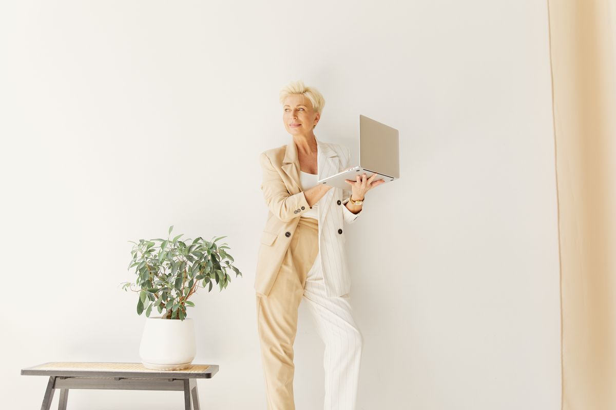 Financial Independence and Empowerment for Older Women 6 Stylish older woman holding a laptop in a professional setting