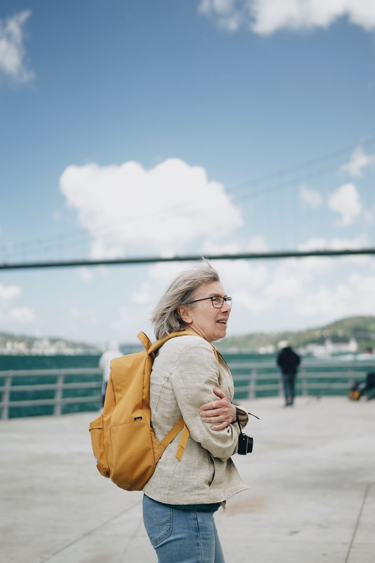 Financial Independence and Empowerment for Older Women 3 Elderly woman with a backpack enjoying a scenic waterfront