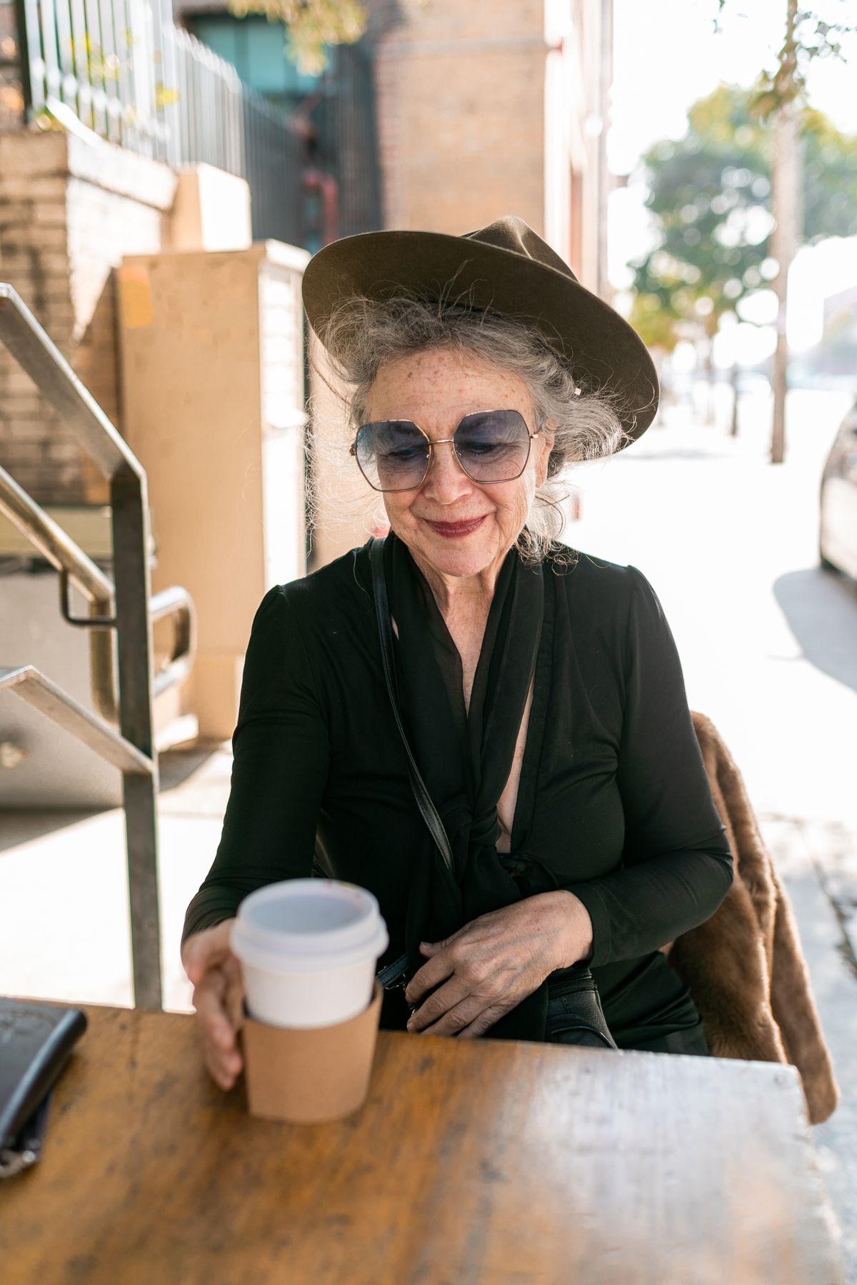 The Beauty, Strength, and Wisdom of Older Women: Embracing Life with Confidence 5 Senior woman in a hat and sunglasses enjoying coffee outdoors