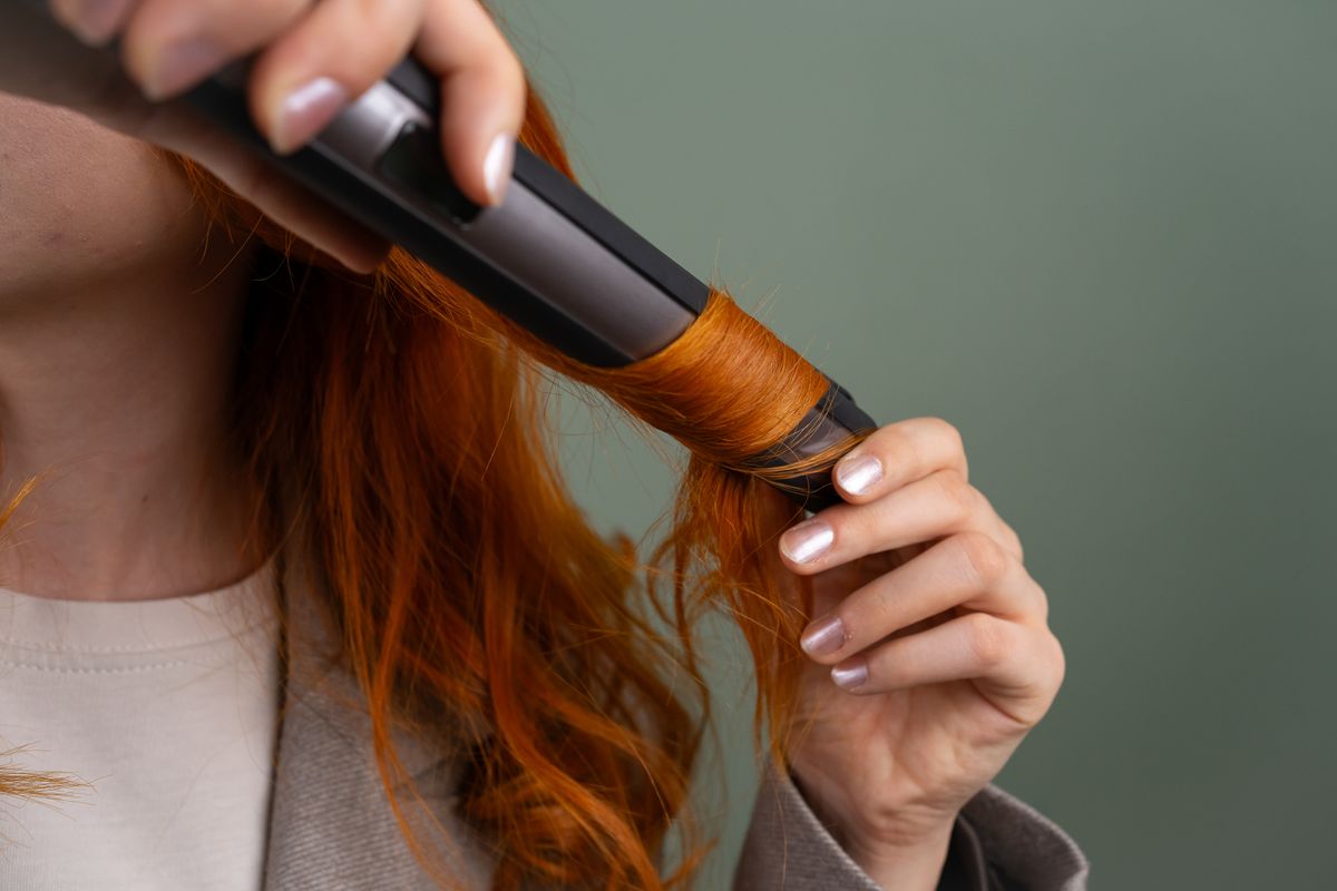 The Shag Haircut: Effortless, Edgy & Full of Texture 2 Woman curling her shag haircut with a curling iron