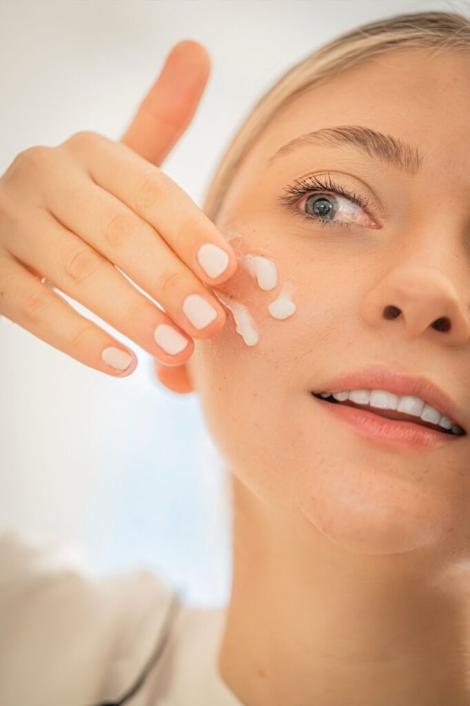 Woman applying moisturizer to her face as part of a daily skincare routine