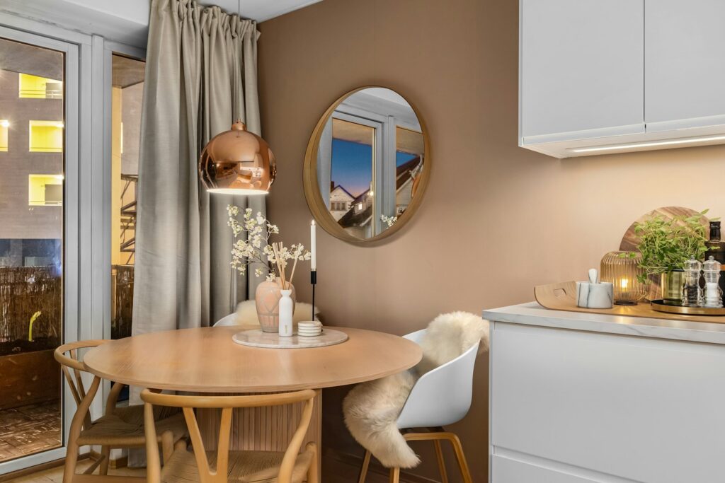 Small kitchen and dining nook with round table, pendant light, and round mirror