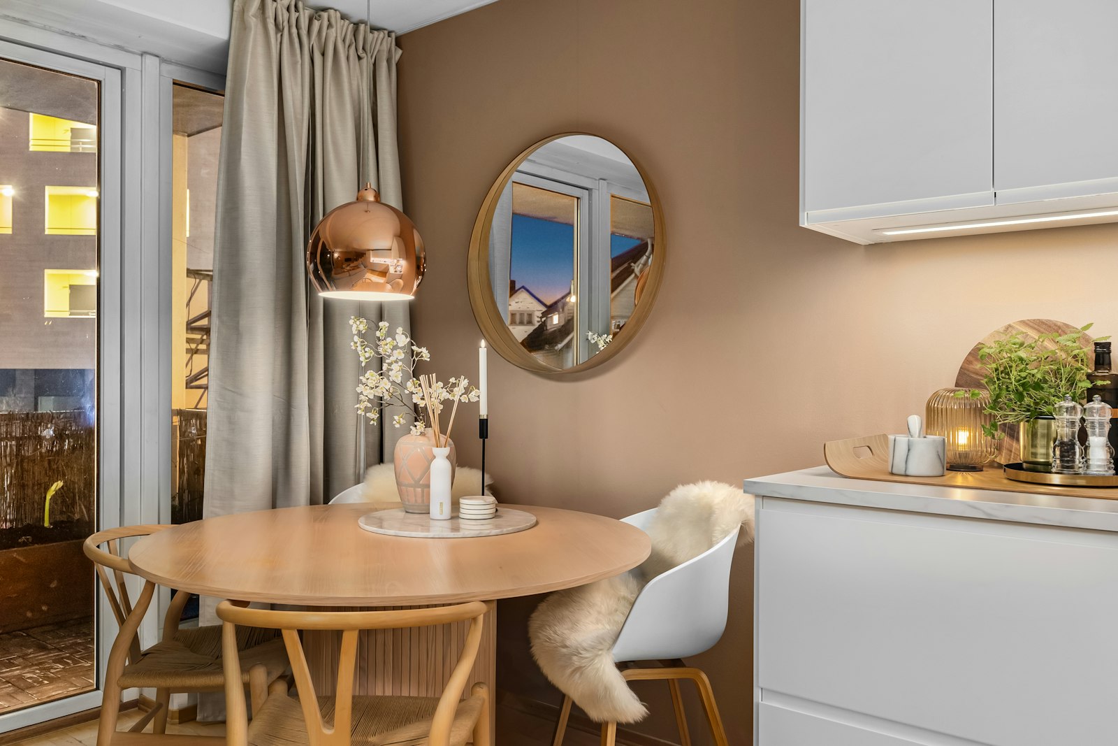Small kitchen and dining nook with round table, pendant light, and round mirror