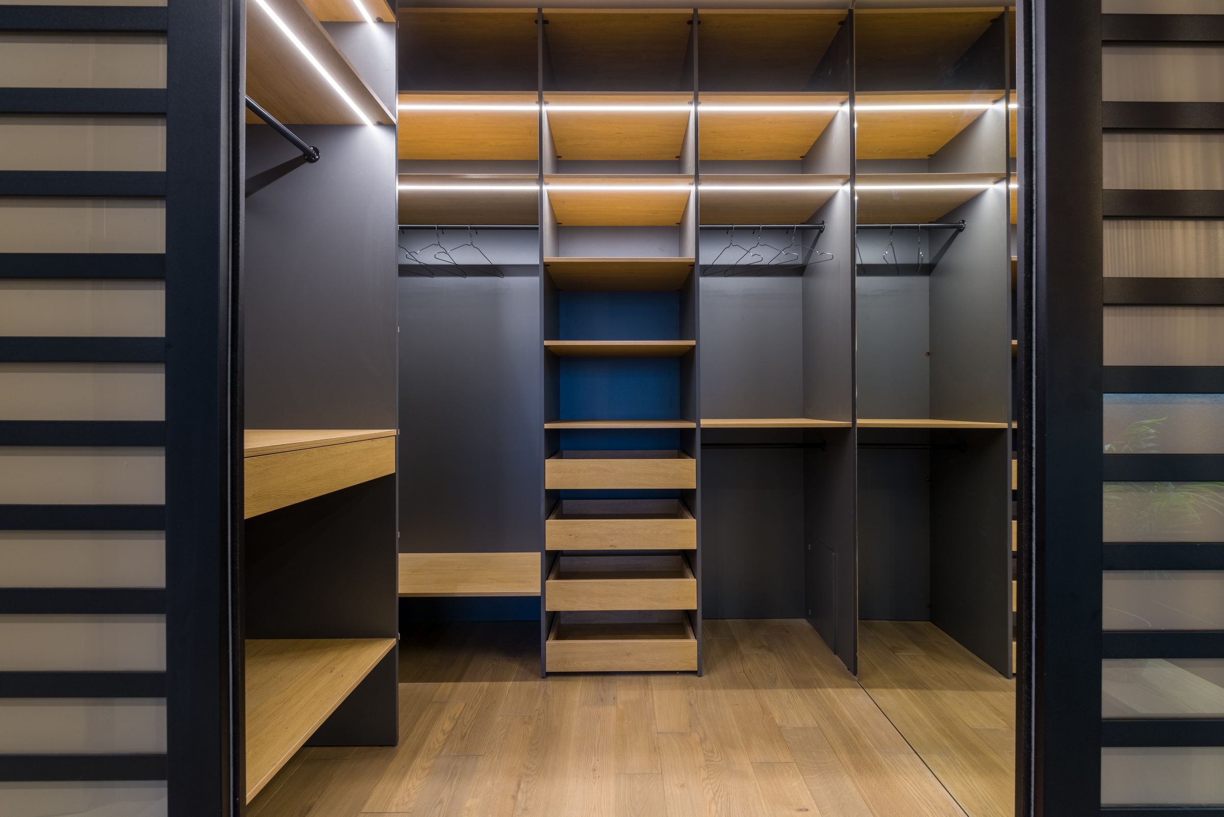 Closet Organization Ideas That Actually Make Getting Dressed Easier 8 Built in closet shelving with warm ambient lighting and wood tones, photo by Max Vakhtbovych via Pexels